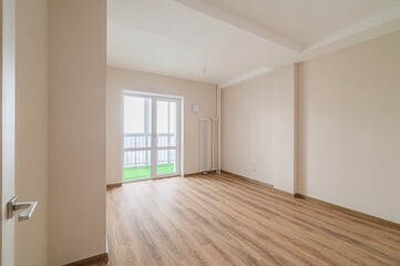 Empty room with wood floor, beige walls, and a balcony. Bright and clean