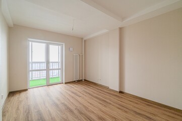 empty room features light walls, wood flooring, and a balcony. A radiator sits near the balcony...