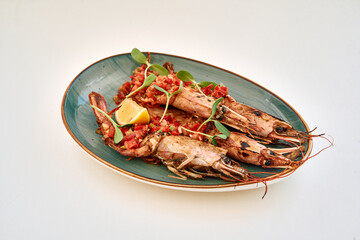 Grilled tiger prawns with tomato salsa and lemon on green plate