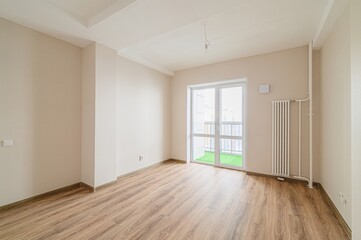 bright, empty room with wood flooring, light beige walls, a white ceiling, and a large glass door leading to a balcony