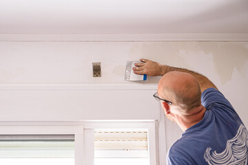 Construction worker plastering wall using putty knife