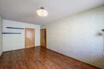 room featuring wooden floors, patterned wallpaper, and a decorative chandelier. Two wooden doors...
