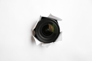 Hidden camera lens through torn hole in white paper