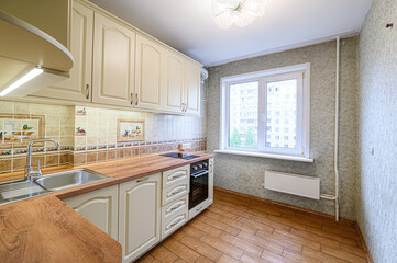 well-lit kitchen featuring light beige cabinets, a wood-like countertop, and a window overlooking a...