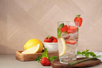 Tasty refreshing drink with strawberries, lemon and mint on wooden table