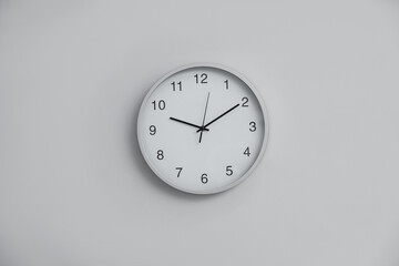 Stylish round clock on white wall indoors