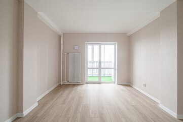 empty room with light walls and wood flooring is bathed in natural light from a balcony door. The room is simple and clean, ready for furnishing