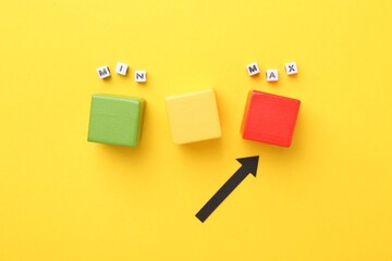 Words Max and Min, cubes and arrow pointing at red one on yellow background, flat lay