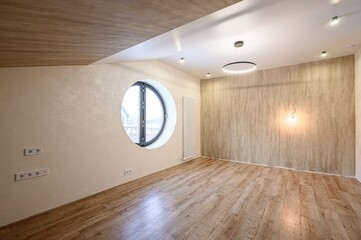 Bright room with wood floor, round window, textured walls, modern lighting. Clean and minimalist...