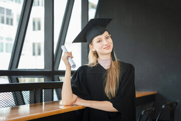 Portrait of a Young Woman on Her Graduation Day, Smiling Female Graduate in Cap and Gown with looking at camera, Proud University Student Celebrating Academic Achievement