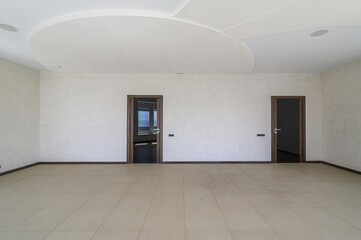 spacious room with tile flooring, textured walls, two dark wood doors, and a unique ceiling design