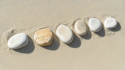 Obraz premium Smooth stones arranged in a line on light sand.
