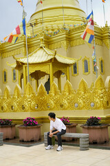 Fototapeta premium an asian chinese man Sitting by a Golden Ornate Temple with Decorative Surroundings