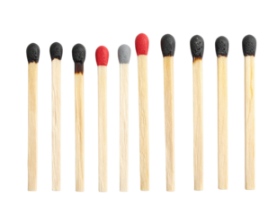 Ten wooden matches with variously burnt or intact heads arranged in a row on a black surface.