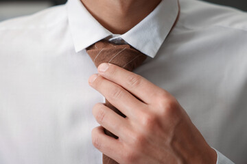 Man tying stylish necktie at home, closeup