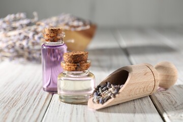 Natural essential oil and lavender flowers on white wooden table, closeup