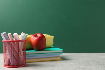 Stylish stationery and red apple on light desk against chalkboard. space for text