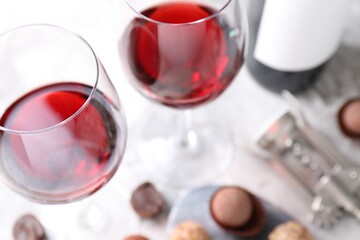 Red wine in glasses and truffle bonbons on light table, selective focus