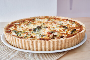 Delicious broccoli cheese quiche on woven placemat with crispy pastry crust