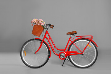 Bicycle with basket of beautiful flowers on grey background