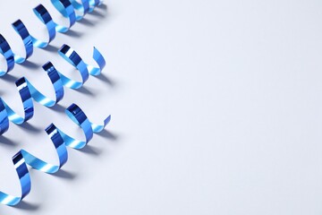 Shiny serpentine streamers on white background, above view. Space for text