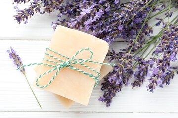 Soap bars and lavender flowers on white wooden table, flat lay