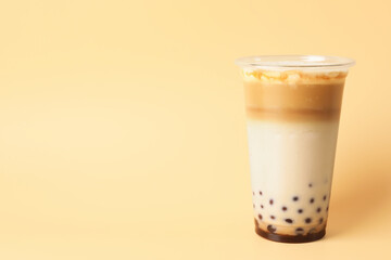Tasty milk bubble tea in plastic cup on beige background, space for text