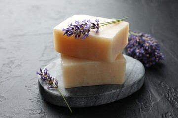 Aromatic soap bars and lavender flowers on dark textured table, closeup
