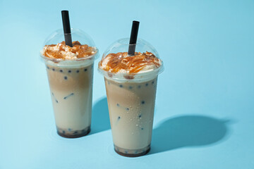 Tasty milk bubble tea in plastic cups on light blue background