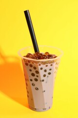 Tasty milk bubble tea in glass on yellow background