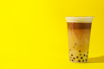 Tasty milk bubble tea in plastic cup on yellow background. Space for text