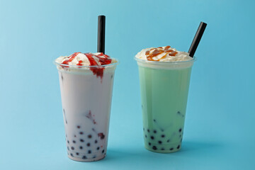 Tasty milk bubble tea in plastic cups on light blue background