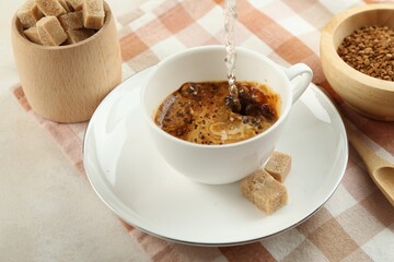 Pouring hot water into cup with instant coffee at light table, closeup