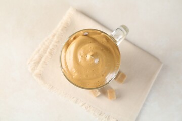 Delicious dalgona coffee in glass cup and brown sugar on light table, flat lay