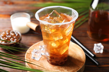 Tasty iced bubble tea and ingredients on wooden table, closeup
