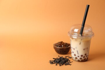 Tasty iced bubble tea and ingredients on orange background. Space for text