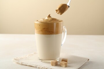 Taking cream from delicious dalgona coffee and brown sugar at light table, closeup