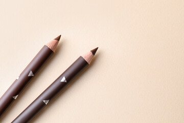 Different eyebrow pencils on beige background, top view. Space for text