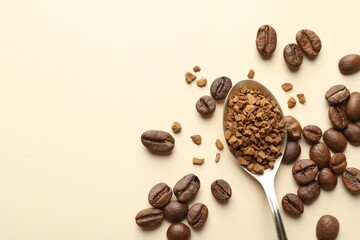 Spoon with instant coffee and beans on beige background, flat lay. Space for text