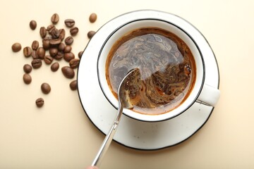 Putting instant coffee into cup on beige background, top view