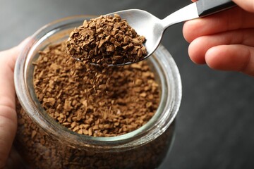 Woman taking instant coffee from jar at table, closeup