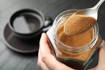 Woman taking instant coffee from jar at table, closeup