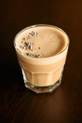 Creamy lavender latte with foamy top in glass on wooden table