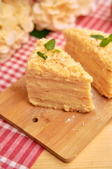Delicious layered napoleon cake on wooden board with mint garnish