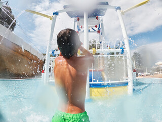 Child playing in water park with interactive splash structure