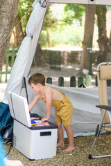 Curious child exploring portable fridge content during family camping trip