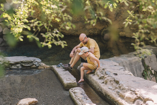 Father and son relaxing by water on camping trip