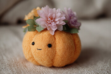 Cute pumpkin with handmade flower crown on textured surface