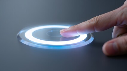 Close up of a finger pressing a glowing blue and white circular button on a dark surface