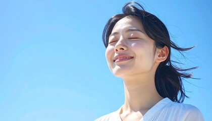 快晴の中で髪を風になびかせた若い日本人女性,A young Japanese woman with her hair blowing in the wind under a clear blue sky.